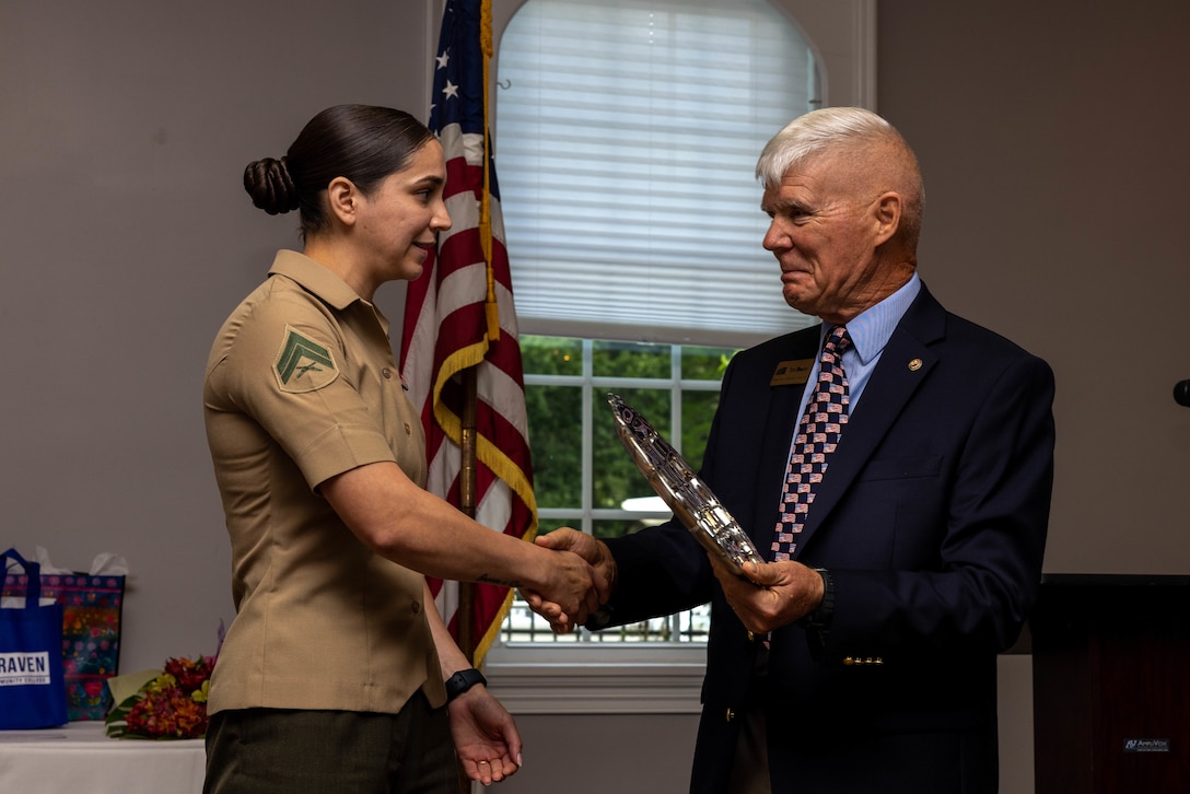 Retired U.S. Marine Corps Maj. Gen. Tom Braaten congratulates Cpl. Maria Villa Silva, an administrative specialist assigned to Headquarters and Headquarters Squadron, Marine Corps Air Station Cherry Point, at a Service Person of the Quarter ceremony at the New Bern Golf and Country Club, New Bern, North Carolina, Sept. 14, 2023. Villa Silva was recognized for her efforts of volunteering on the installation and in the surrounding communities. (U.S. Marine Corps photo by Lance Cpl. Lauralle Walker)