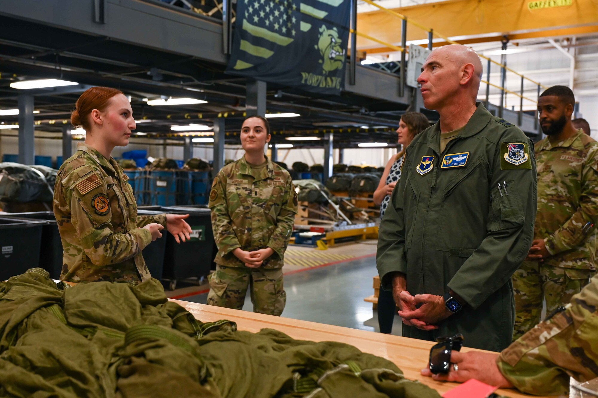 U.S. Air Force Senior Airman Jillian Barr, 97th Logistics Readiness Squadron air transportation specialist, shows Maj. Gen. Clark Quinn, 19th Air Force commander, the process of packaging parachutes for the C-17 Globemaster III airdrops at Altus Air Force Base, Oklahoma, Sept. 20, 2023. The process includes packing 64 feet of parachute and securing two tons of material onto a hand-assembled pallet while safely executing its transportation to the aircraft. (U.S. Air Force photo by Airman 1st Class Kari Degraffenreed)