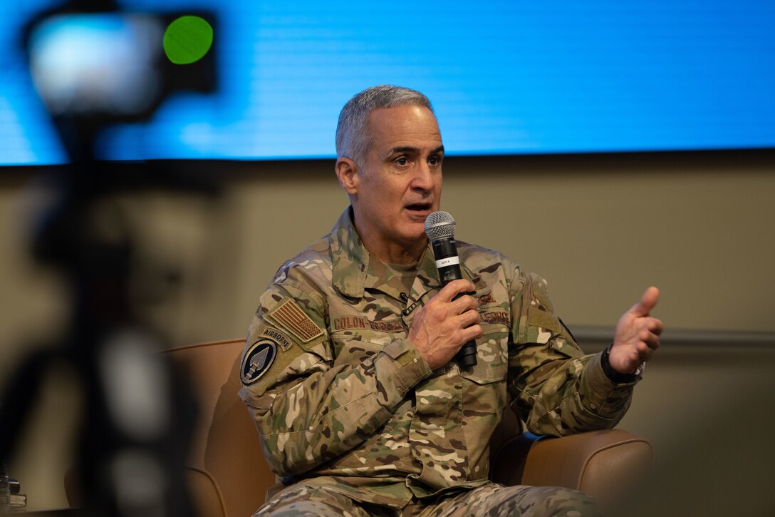 An Air Force military member sitting on a couch and speaking with a mic.