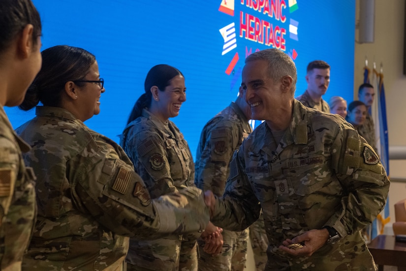 An Air Force man in uniform presenting his coin to a row of service members.