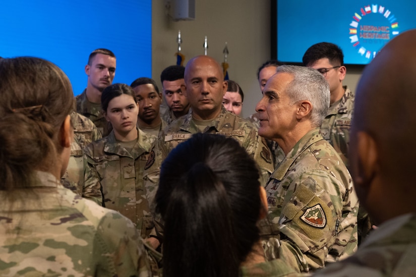 An Air Force military leader in camouflage uniform speaking to a group of other Air Force members of lower rank.