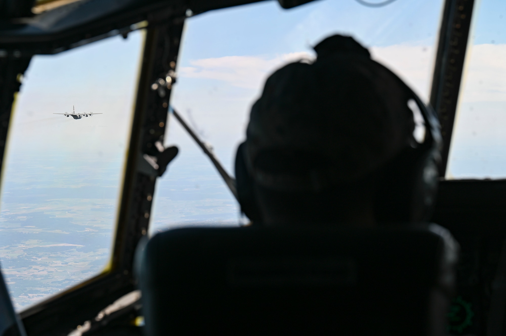 An airforce pilot views a C-130 Hercules aircraft from the cockpit while flying during Air Defender 2023