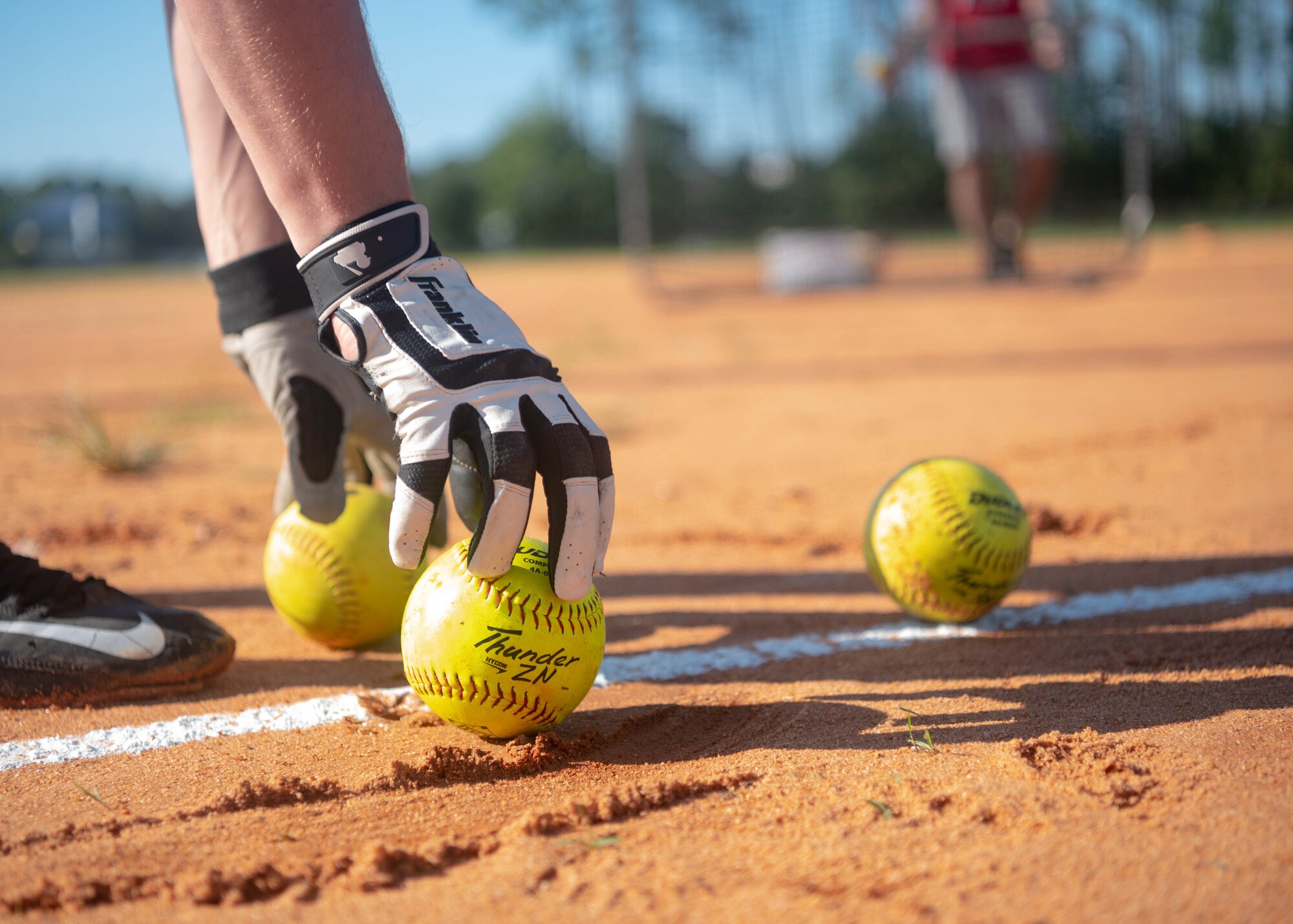 Man picks up a softball.