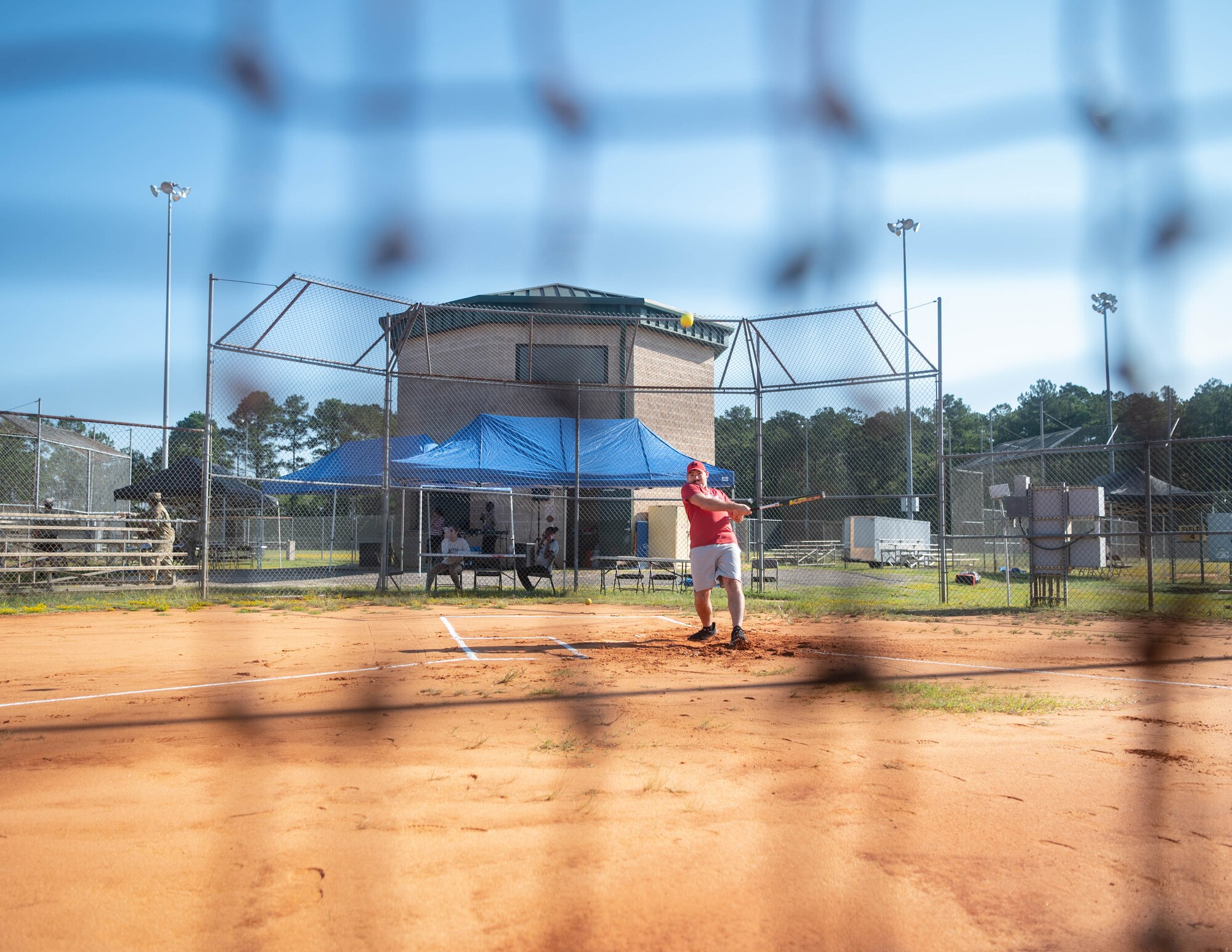 Man prepares to swing bat at a softball.