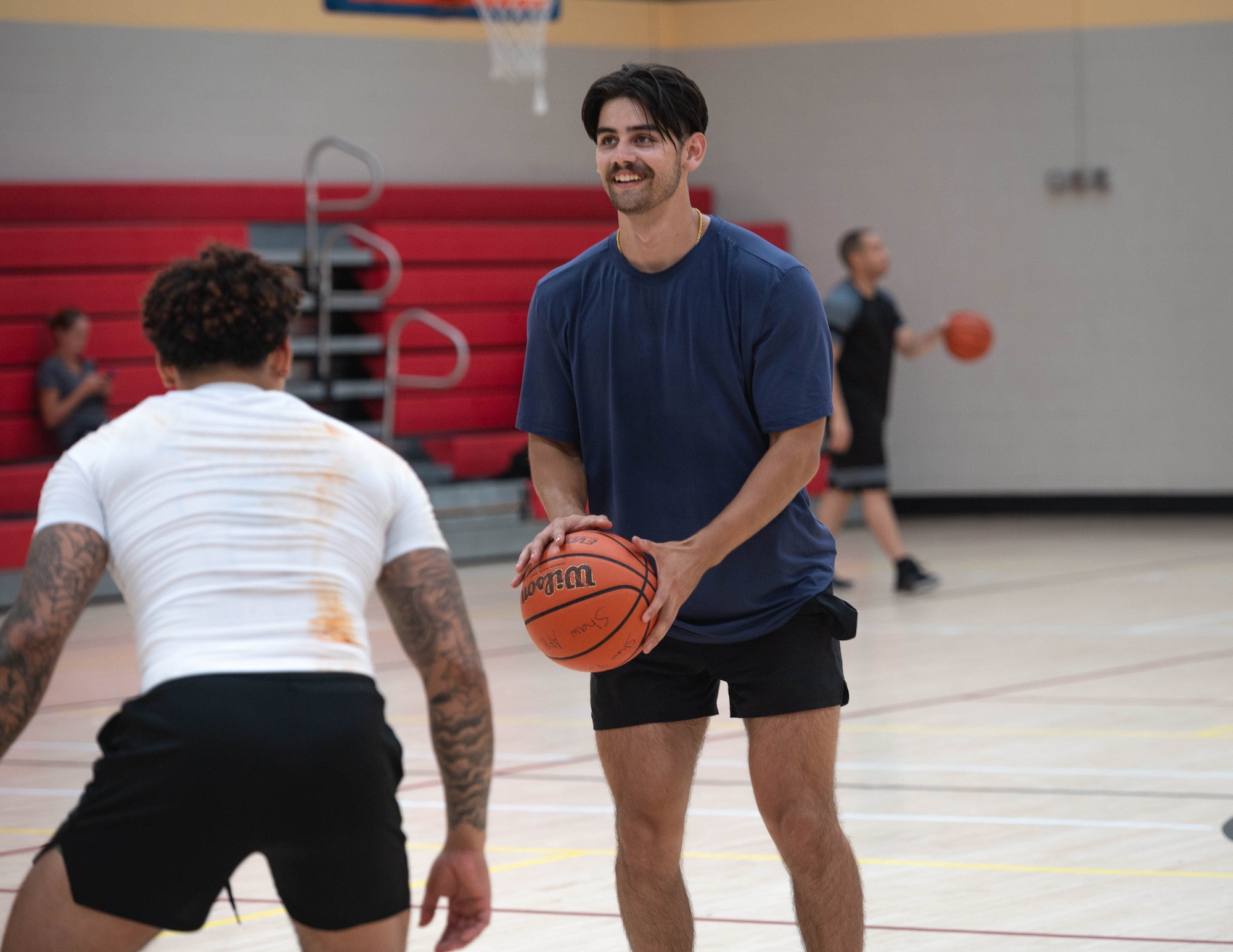 Two people play basketball on a court.