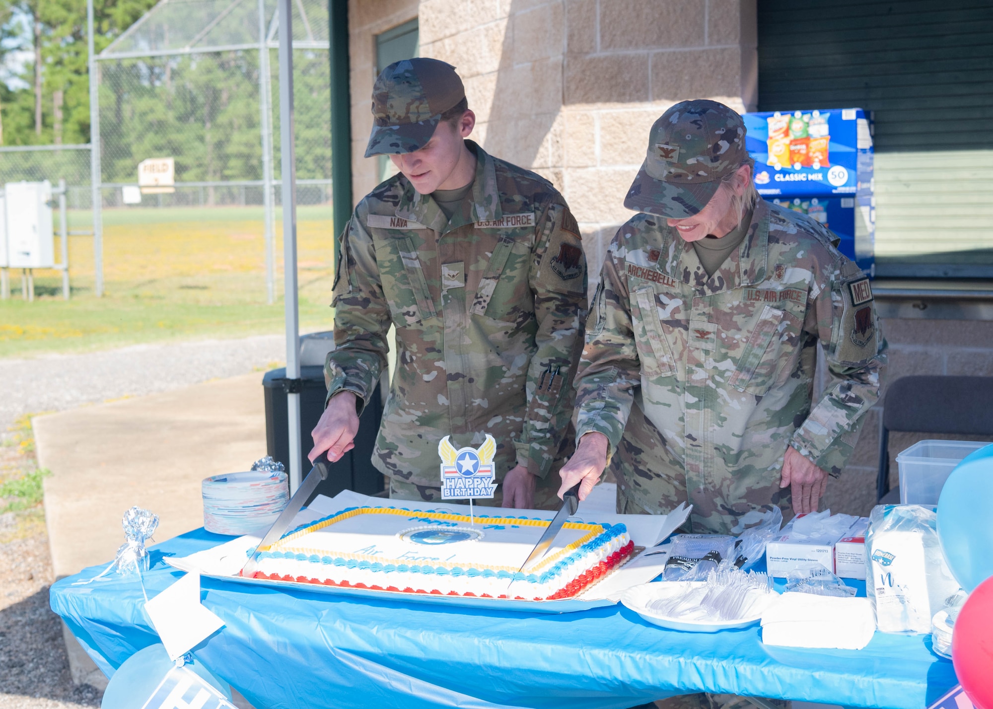 Two service members simultaneously cut a cake celebrating the 20th Fighter Wing Sports Day and the U.S. Air Force birthday.