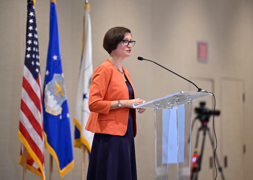 A woman stands at a lectern.