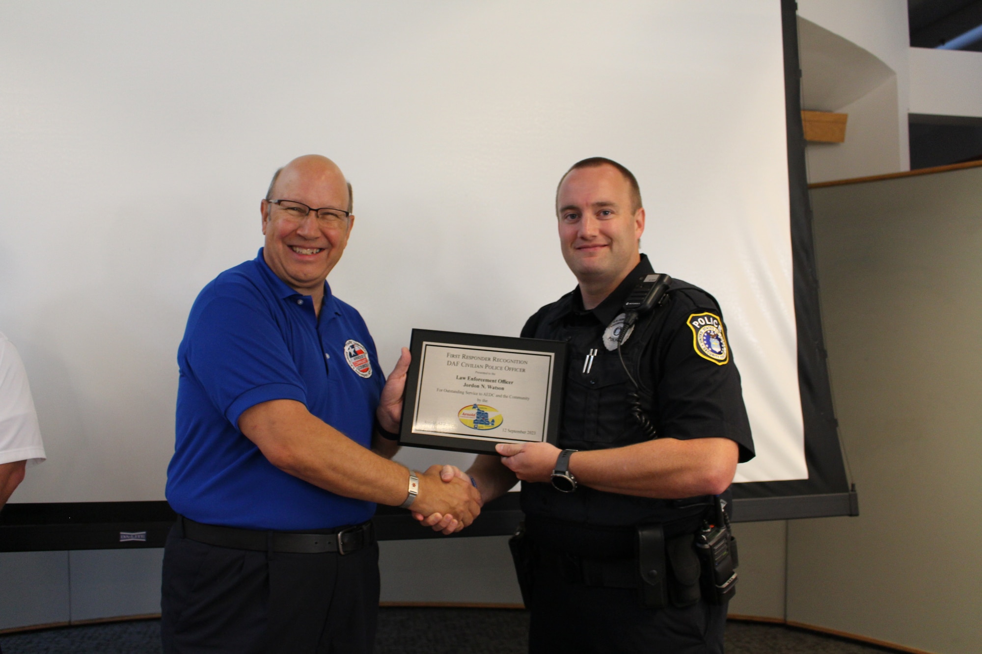 Glenn Liston, Arnold Community Council president, left, presents Nick Watson, officer with the Department of the Air Force Police Officers at Arnold Air Force Base, with a plaque after recognizing him as an outstanding first responder during a meeting of the ACC at the Gossick Leadership Center at Arnold AFB, Tenn., headquarters of Arnold Engineering Development Complex, Sept. 12, 2023. Watson was one of three recipients of the 2023 Arnold Community Council First Responder Awards. (U.S. Air Force photo by Kali Bradford)