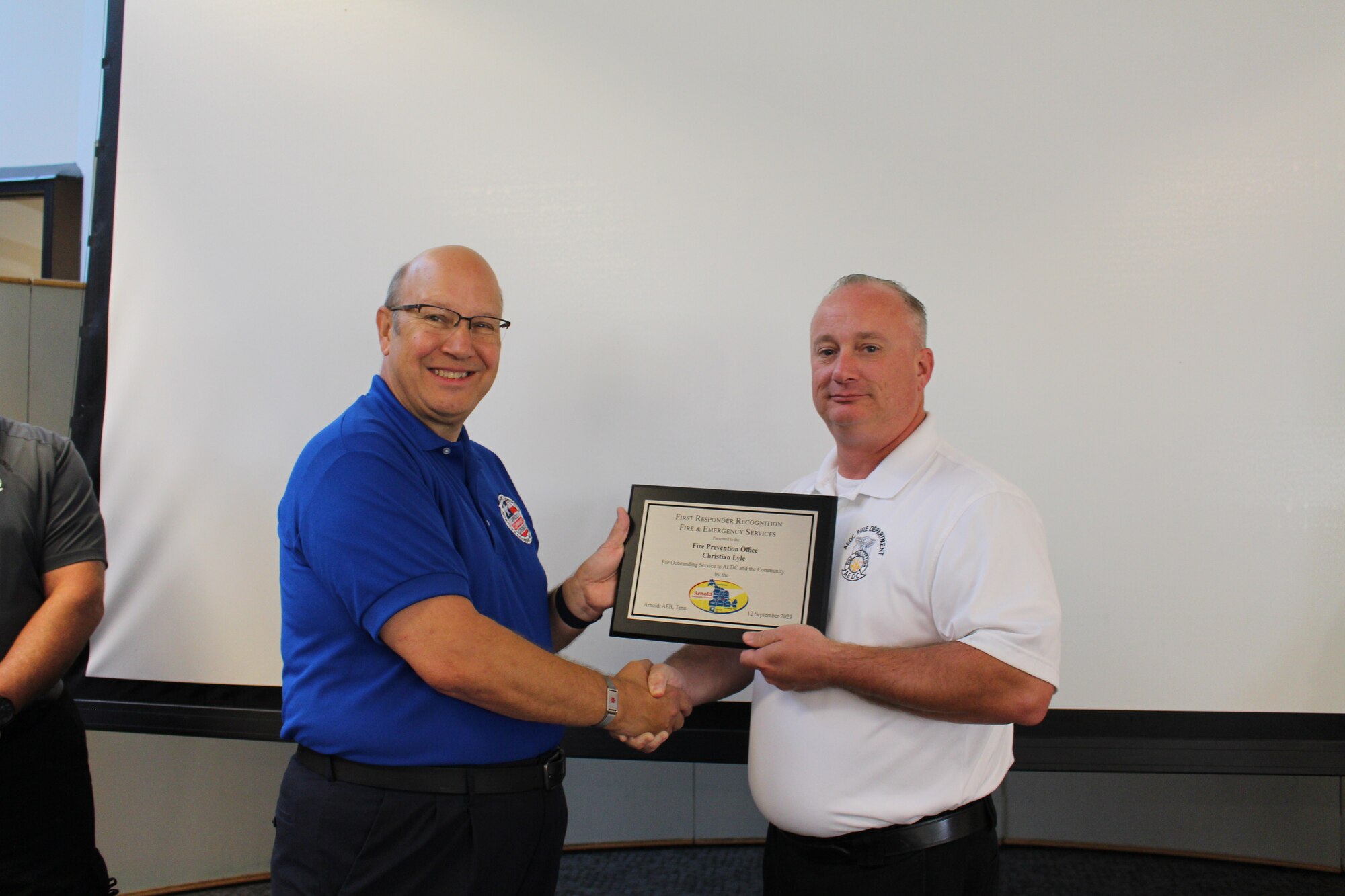 Glenn Liston, Arnold Community Council president, left, presents Christian Lyle, fire prevention officer with Arnold Air Force Base Fire and Emergency Services with a plaque after recognizing him as an outstanding first responder during a meeting of the ACC at the Gossick Leadership Center at Arnold AFB, Tenn., headquarters of Arnold Engineering Development Complex, Sept. 12, 2023. Lyle was one of three recipients of the 2023 Arnold Community Council First Responder Awards. (U.S. Air Force photo by Kali Bradford)