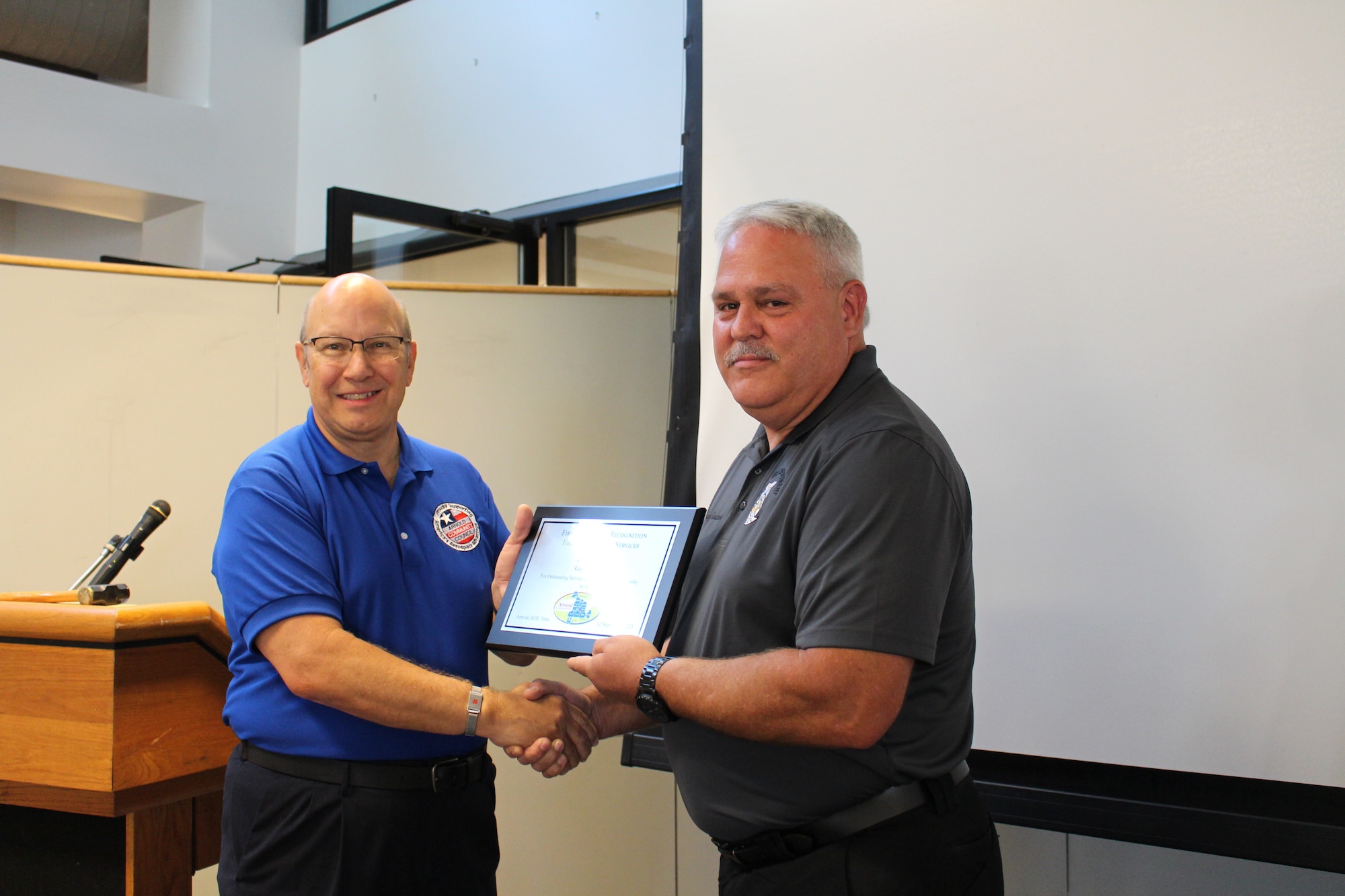 Glenn Liston, Arnold Community Council president, left, presents Arnold Air Force Base Fire and Emergency Services Fire Inspector Guy Chastain with a plaque after recognizing him as an outstanding first responder during a meeting of the ACC at the Gossick Leadership Center at Arnold AFB, Tenn., headquarters of Arnold Engineering Development Complex, Sept. 12, 2023. Chastain was one of three recipients of the 2023 Arnold Community Council First Responder Awards. (U.S. Air Force photo by Kali Bradford)