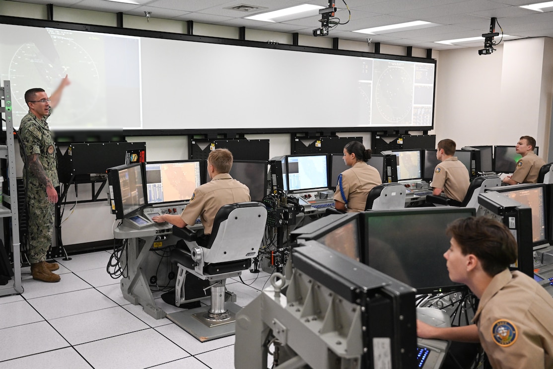 DAHLGREN, Va. (Sept. 25, 2023) Surface Combat Systems Training Command AEGIS Training and Readiness Center’s Warfare Tactics Instructor Lt. Robert Joiner provides a training demonstration in the Reconfigurable Combat Information Center Trainer (RCT) to cadets from Stafford High School’s Navy Junior Reserve Officer's Training Corps during their visit to Naval Support Facility Dahlgren, Sept. 25. The RCT is part of the Director, Surface Warfare’s (OPNAV N96) program of record, Surface Training Advanced Virtual Environment-Combat Systems. These systems are the culmination of eight years of investment in training technologies, devices, and facilities to improve the effectiveness, efficiency, and availability of all surface training. (U.S. Navy photo by Michael Bova)