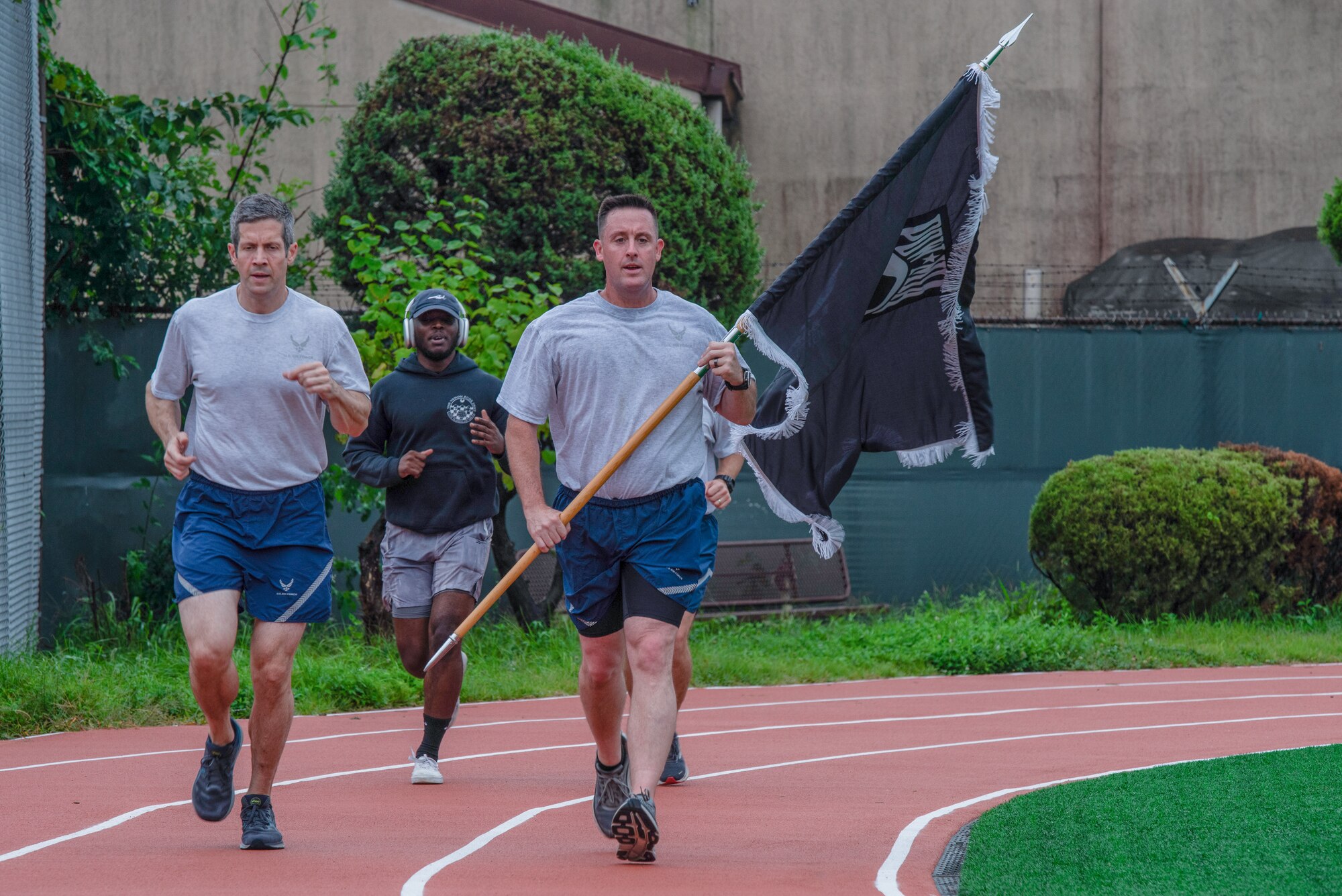 From the left, U.S. Air Force Col. William McKibban, 51st Fighter Wing commander; Senior Airman Exzavier Stevenson, 51st Operational Support Squadron all source analyst; Chief Master Sgt. Joshua Trundle, 51st FW command chief, run with a prisoner of war and missing in action flag during a 24-hour POW/ MIA remembrance run at Osan Air Base, Republic of Korea, Sept. 26, 2023. Service members from across the wing came to attend the ceremonies and participate in the run, showing support for their wingmen and honoring those who were captured or went missing in combat. (U.S. Air Force photo by Airman 1st Class Chase Verzaal)
