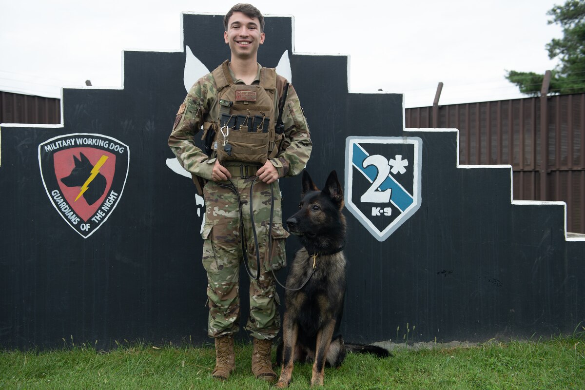 A military man and a dog pose for a photo.