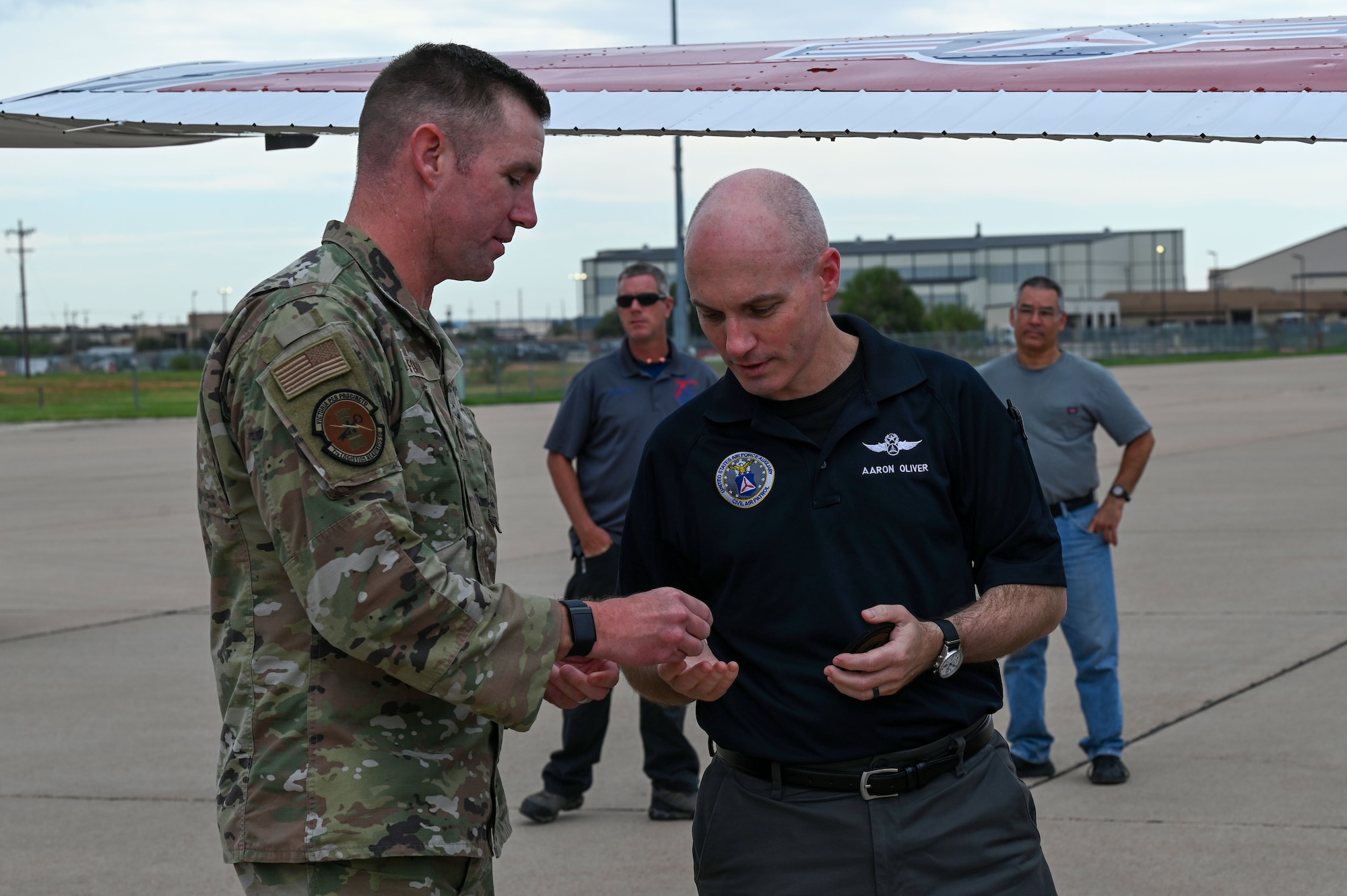 Capt. Christopher Ford, 7th Logistics Readiness Squadron director of operations, presents Col. Aaron Oliver, Oklahoma Wing Civil Air Patrol commander, with a coin and patch at Dyess Air Force Base, Texas, Sept. 21, 2023. This mission underscores the crucial support provided by the CAP in bolstering Air Force Global Strike Command's role in national defense. (U.S. Air Force photo by Senior Airman Sophia Robello)