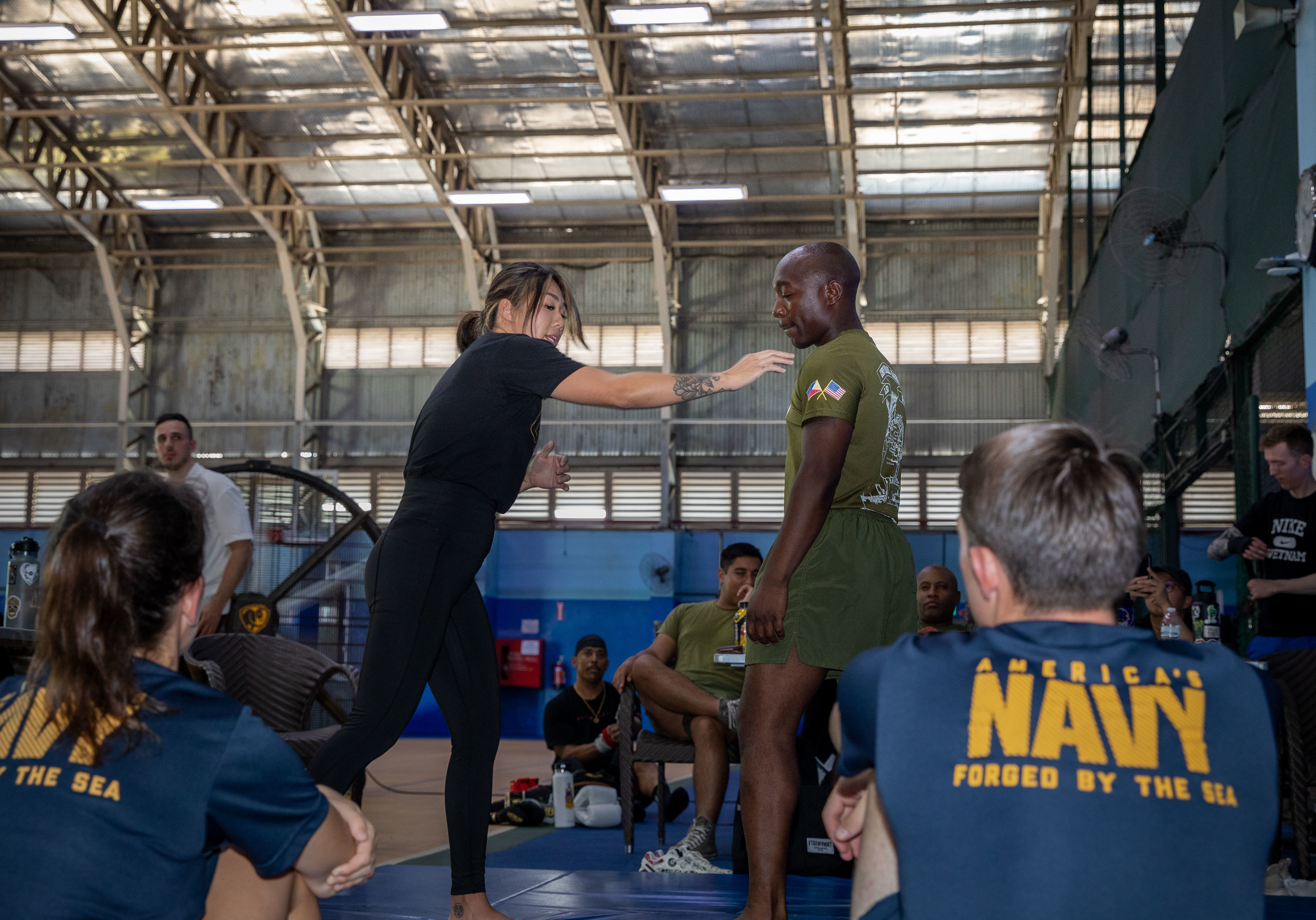 Angela “Unstoppable” Lee, left, demonstrates a double-leg takedown to Sailors and Marines from USS Pearl Harbor (LSD 52) during a port stop in Singapore for Pacific Partnership 2023.