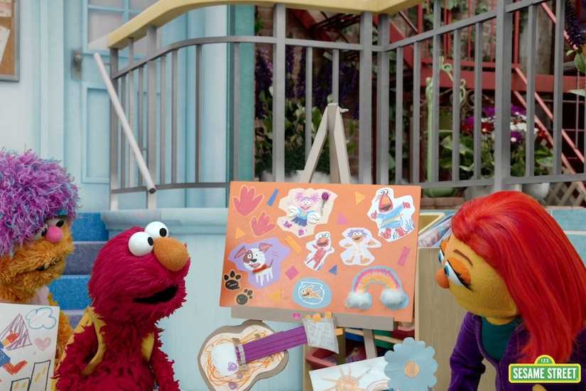 A still photo showing three muppets and an easel.