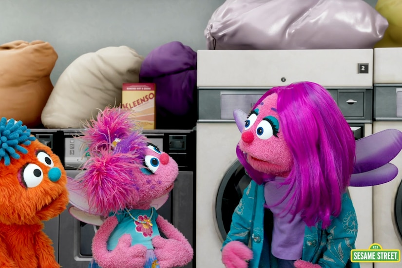 A still photo showing three muppets in front of laundry machines.