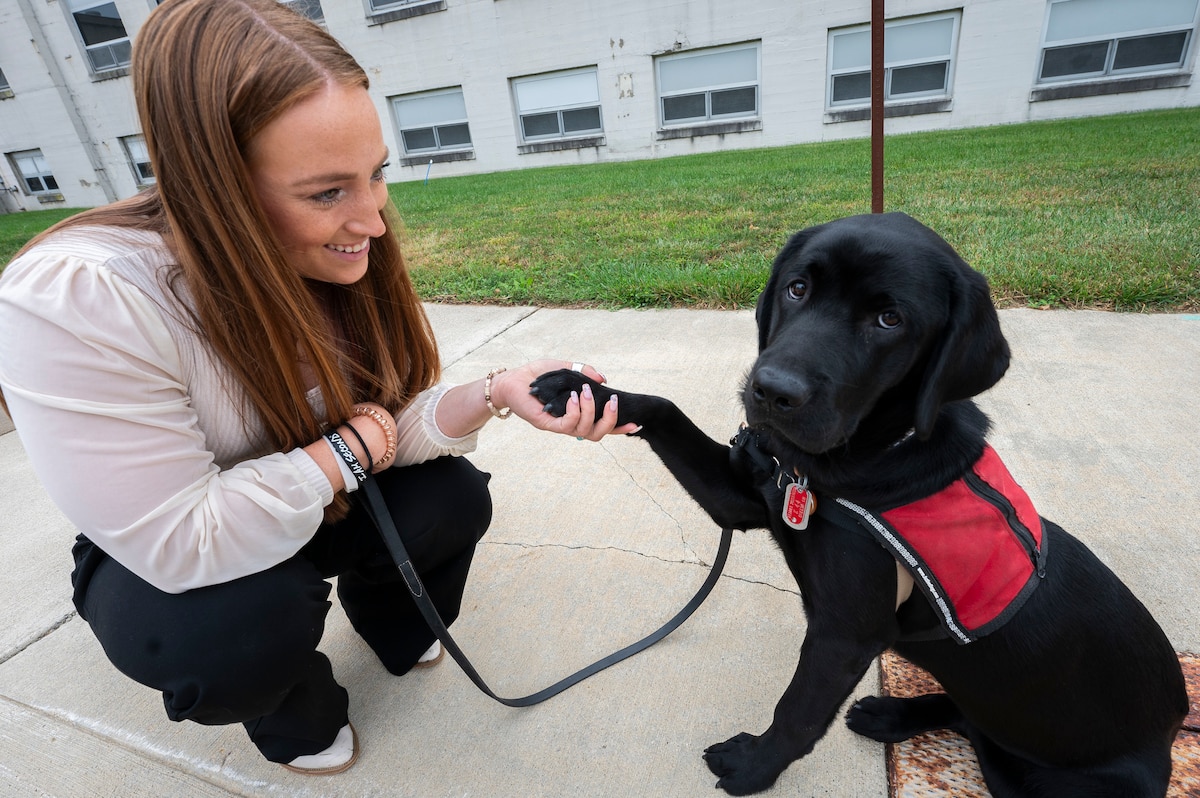 Woman crouches with dog outside building. (USAF photo by Jim Varhegyi).