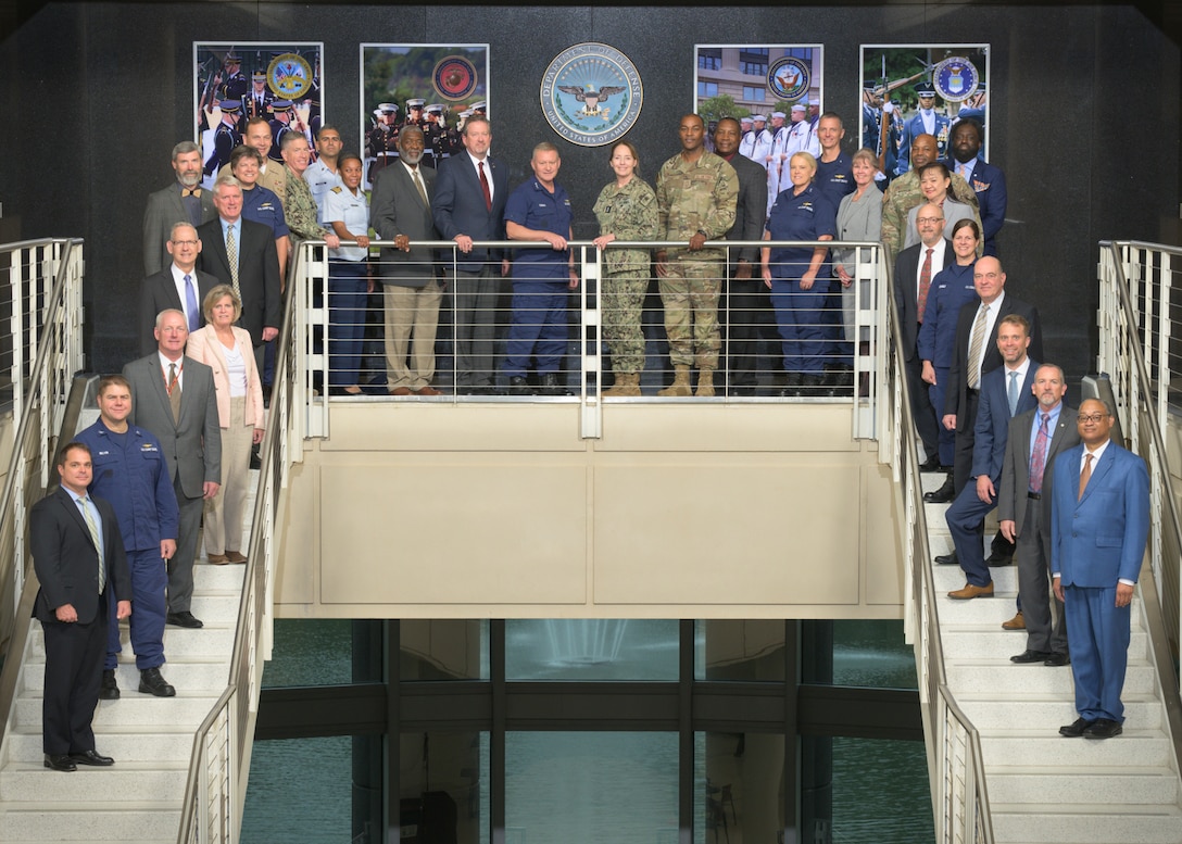 Representatives from the Defense Logistics Agency and the Coast Guard pose on a stairwell.