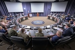 A photo of from behind a round table in a conference room. Representatives from the Coast Guard and the Defense Logistics Agency are sitting around the table.