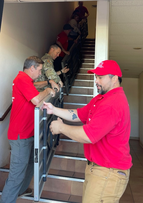 A group of people carry tables up a set of stairs.