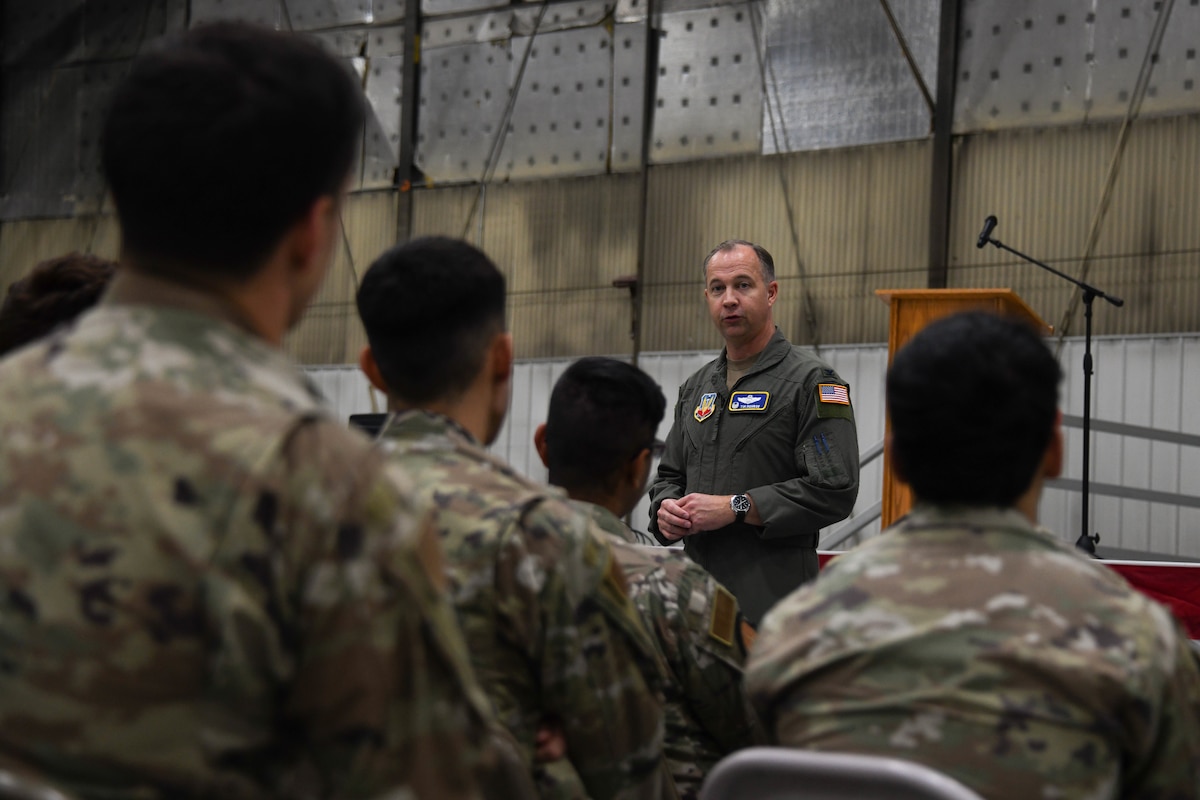A man in a flight suit talks to a group of military members.