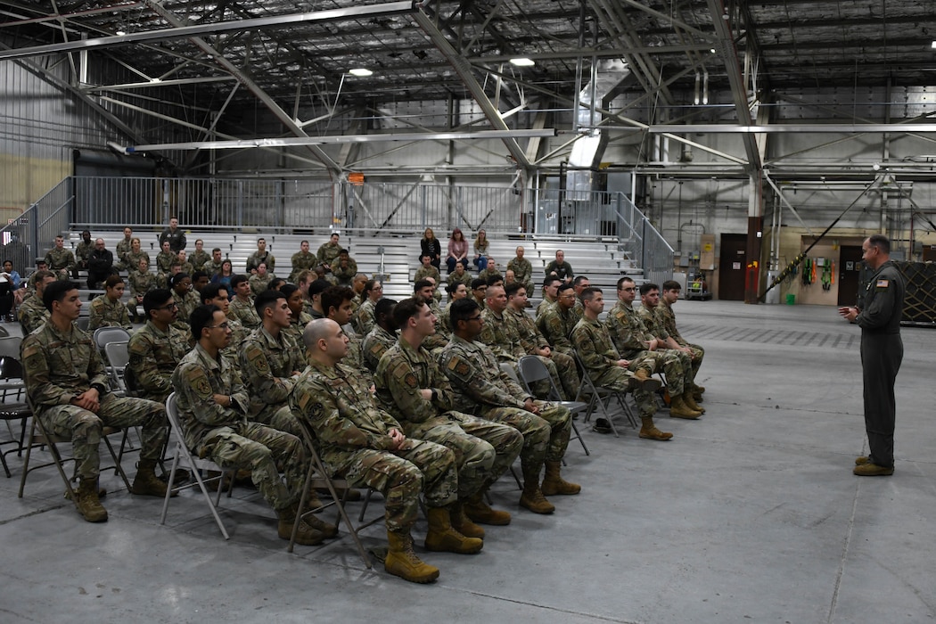 A man in a flight suit talks to a group of military members.