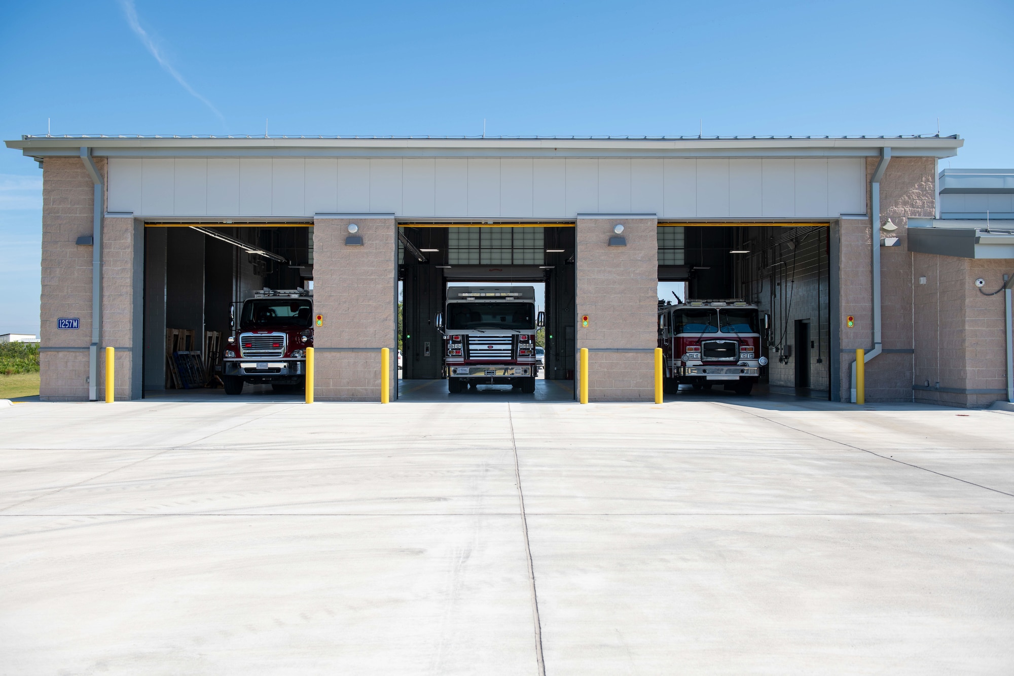 Three rescue trucks parked in the bay of a fire station.