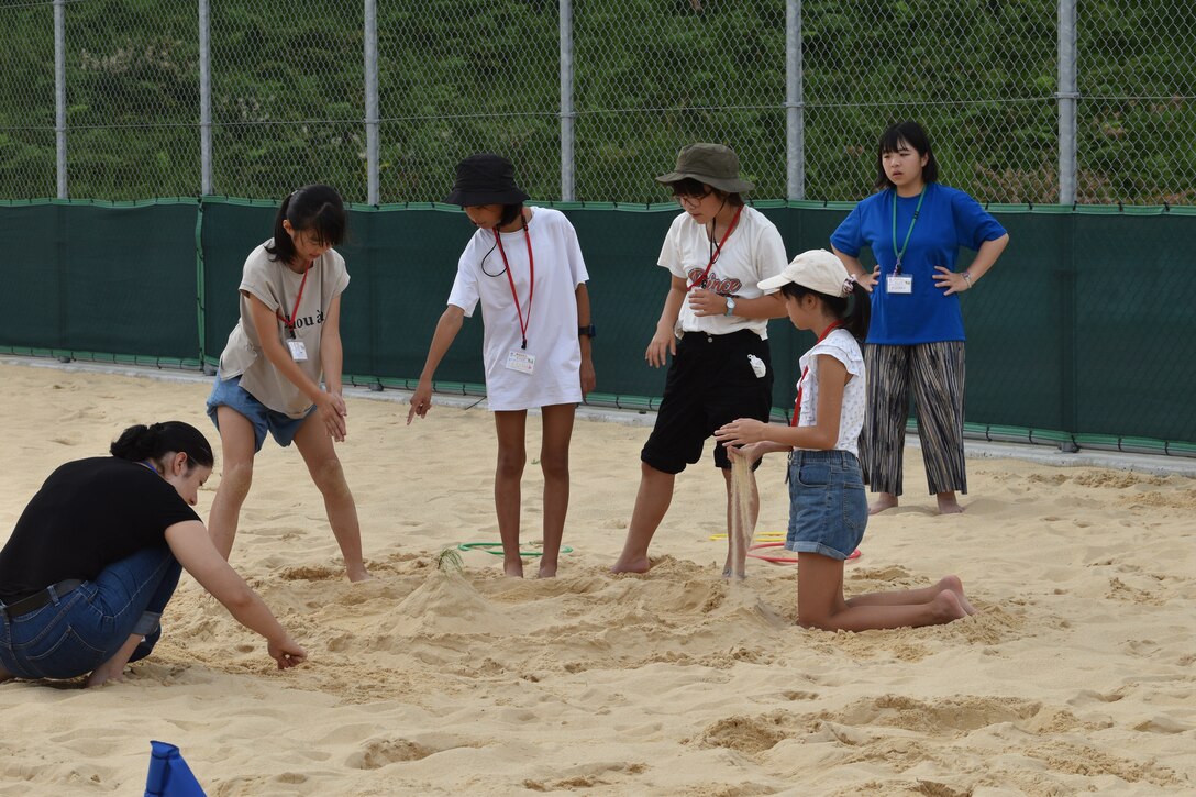 Corporal Brissenia Rojo plays in the sand with girls.