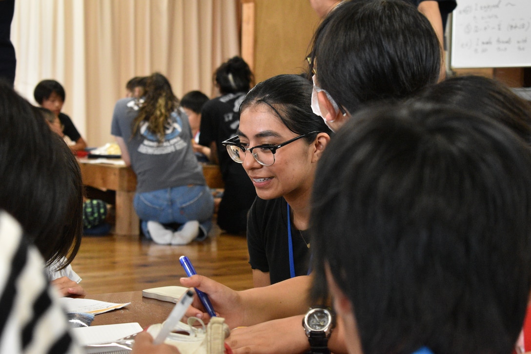 Sergeant Selene Cruz Alavez, a supply clerk with the CATC Camp Fuji distribution management office assigned to CATC Camp Fuji, watches over a child as they write about their experiences during English Camp, September 18, 2023. CATC Camp Fuji Marines mentored Japanese children through English Camp emersion course hosted by the National Chuo Youth Friendship Center in Gotemba, Japan.  (U.S. Marine Corps photo by Song Jordan)