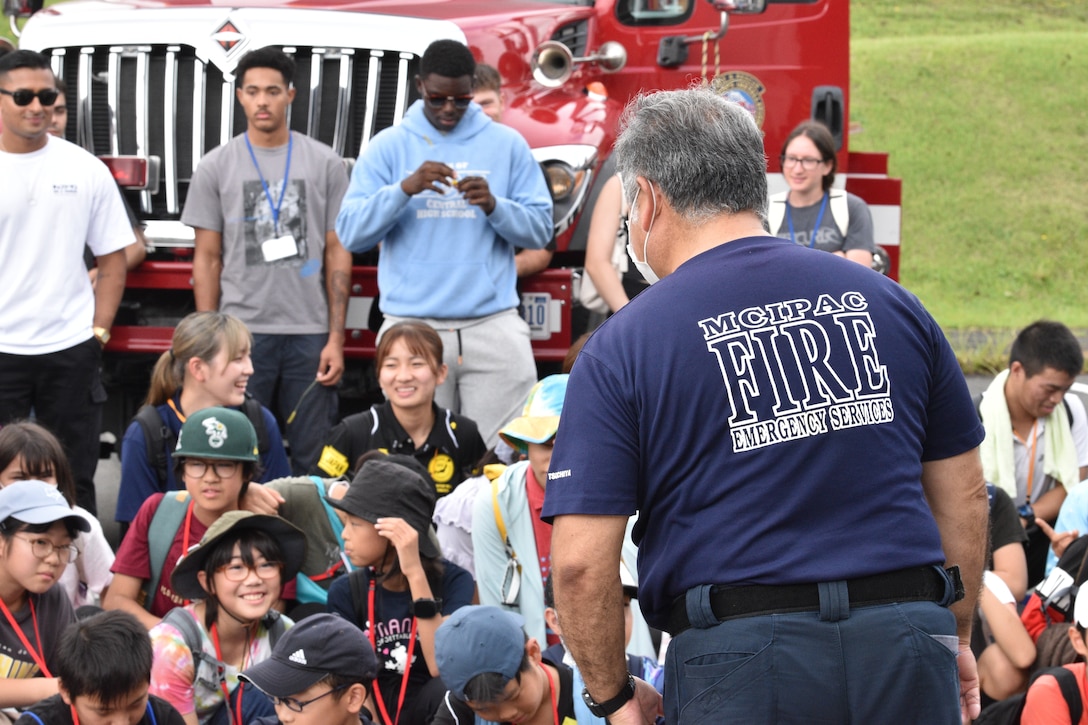 A CATC Camp Fuji firefighter encourages children to ask questions during their visit to the installation, September 17, 2023. CATC Camp Fuji Marines mentored Japanese children through English Camp emersion course hosted by the National Chuo Youth Friendship Center in Gotemba, Japan.  (U.S. Marine Corps photo by Song Jordan)