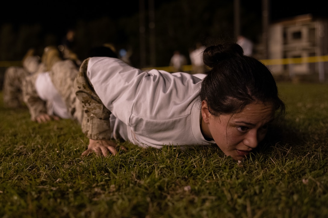 U.S. Marine Corps LCpl. Isis Gil executes squad push-ups during a Marine Corps Martial Arts Program culminating event on Camp Courtney, Okinawa, Japan, March 15, 2024. MCMAP aims to strengthen the mental and moral resiliency of individual Marines through realistic combative training, warriors' ethos studies, and physical hardening. Gil, a native of Texas, is a Chemical, Biological, Radiological, and Nuclear Responder with Headquarters Battalion, 3d Marine Division. (U.S. Marine Corps photo by Lance Cpl. Adam Trump)