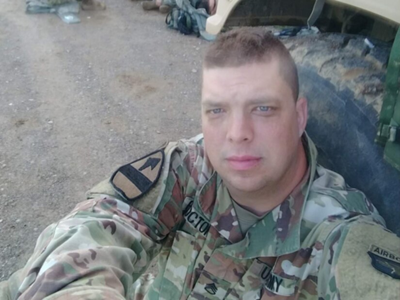 Staff Sgt Adam Proctor resting against Humvee wheel while deployed