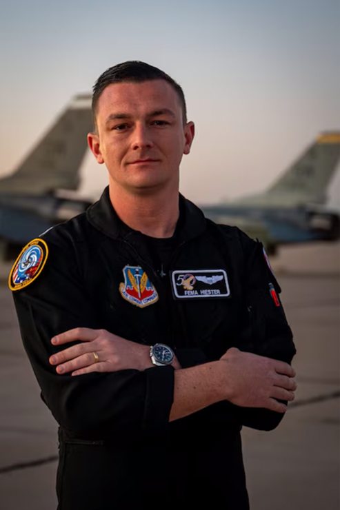 a man in a black uniform standing in front of a row of f-16s