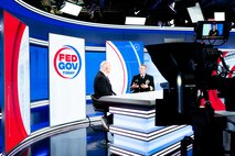 The Director fo U.S. Navy Strategic Systems Programs (SSP) Vice Adm. Johnny R. Wolfe, Jr (right) sits on the news set for Fed Gov Today and talks with host Francis Rose (left), Sunday. You can see the TV cameras in the photo. Rose and Vice Adm. Wolfe are sitting side-by-side at a news desk. In the background is the red, white, and blue show set that has the show's logo on it. The logo reads "Fed Gov Today" and is contained within a half-blue-half-red circle. Vice Adm. Wolfe highlighted SSP's focus on the workforce with new employee onboarding programs like 'SSP Now' and how the initiatives equip the workforce to support SSP's nuclear deterrence mission and support America's Warfighting Navy. SSP is the command that provides cradle-to-grave lifecycle support for the sea-based leg of the nation's nuclear triad.