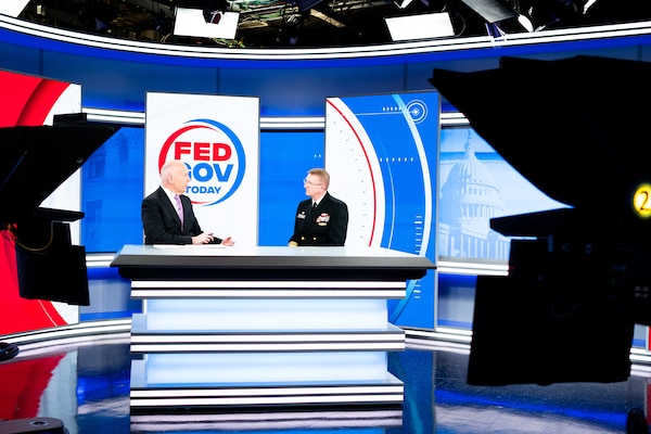 The Director fo U.S. Navy Strategic Systems Programs (SSP) Vice Adm. Johnny R. Wolfe, Jr (right) sits on the news set for Fed Gov Today and talks with host Francis Rose (left), Sunday. You can see the TV cameras in the photo. Rose and Vice Adm. Wolfe are sitting side-by-side at a news desk. In the background is the red, white, and blue show set that has the show's logo on it. The logo reads "Fed Gov Today" and is contained within a half-blue-half-red circle. Vice Adm. Wolfe highlighted SSP's focus on the workforce with new employee onboarding programs like 'SSP Now' and how the initiatives equip the workforce to support SSP's nuclear deterrence mission and support America's Warfighting Navy. SSP is the command that provides cradle-to-grave lifecycle support for the sea-based leg of the nation's nuclear triad.