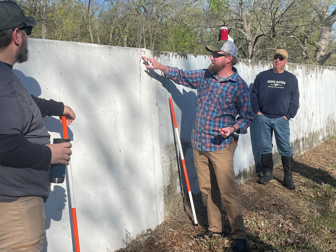 man pointing toward a concrete wall