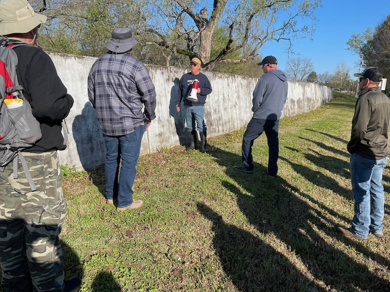 a group of men standing next to a wall