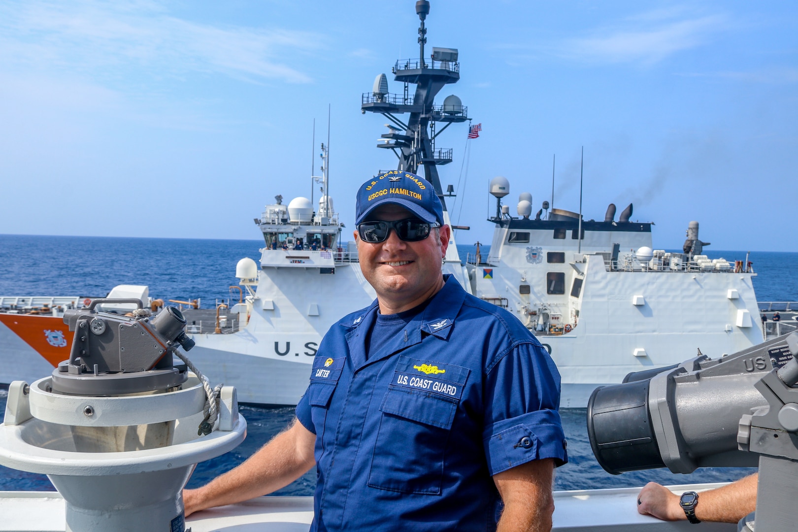 The Commanding Officer of Coast Guard Cutter Hamilton (WMSL 753), Capt. Justin Carter poses for a photo in front of the Coast Guard Cutter Munro (WMSL 755) during an at-sea training in the Pacific Ocean, March 12, 2024. Hamilton and Munro exchanged cutter boats and sailed in formation during this evolution.
