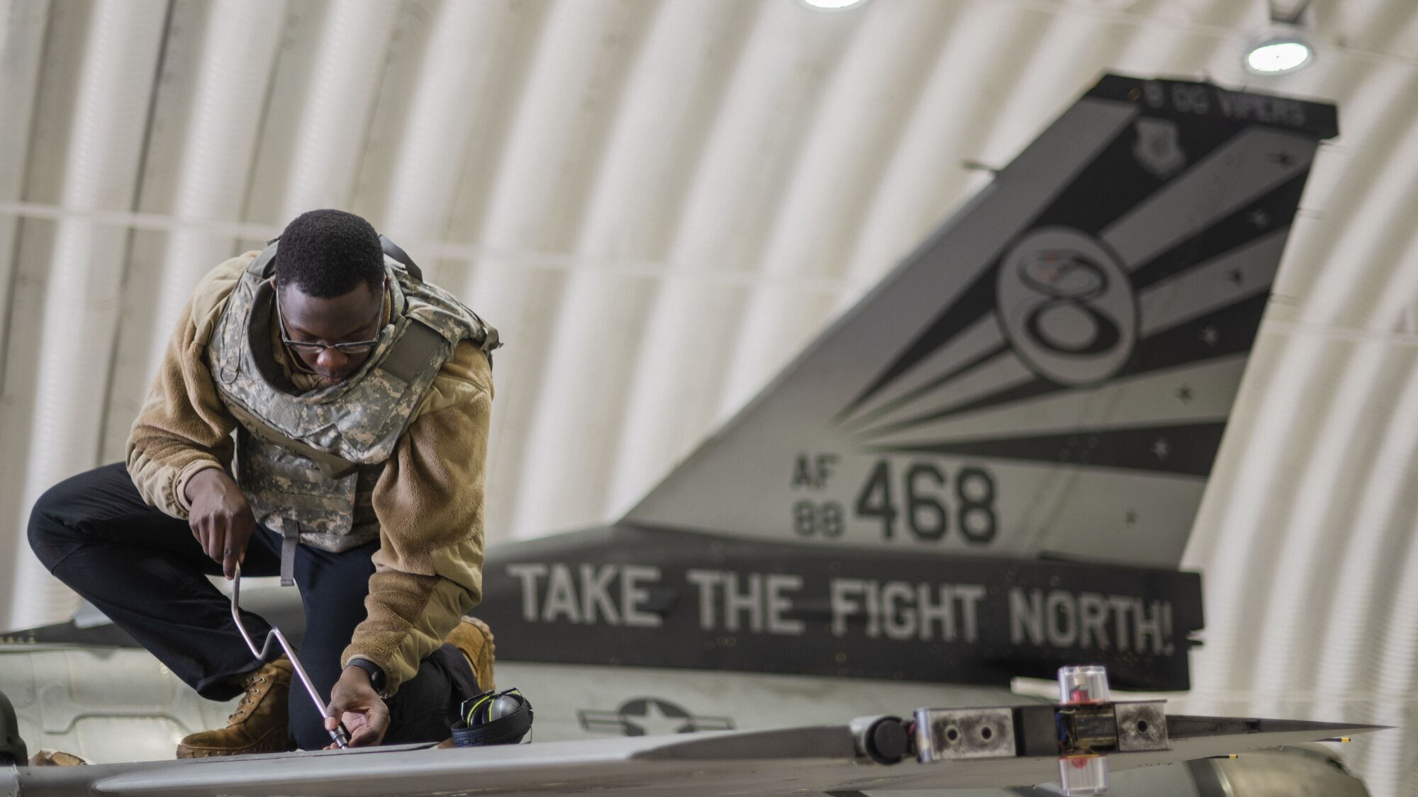 Senior Airman Elvis Atieno performs maintenance on an F-16 Fighting Falcon.