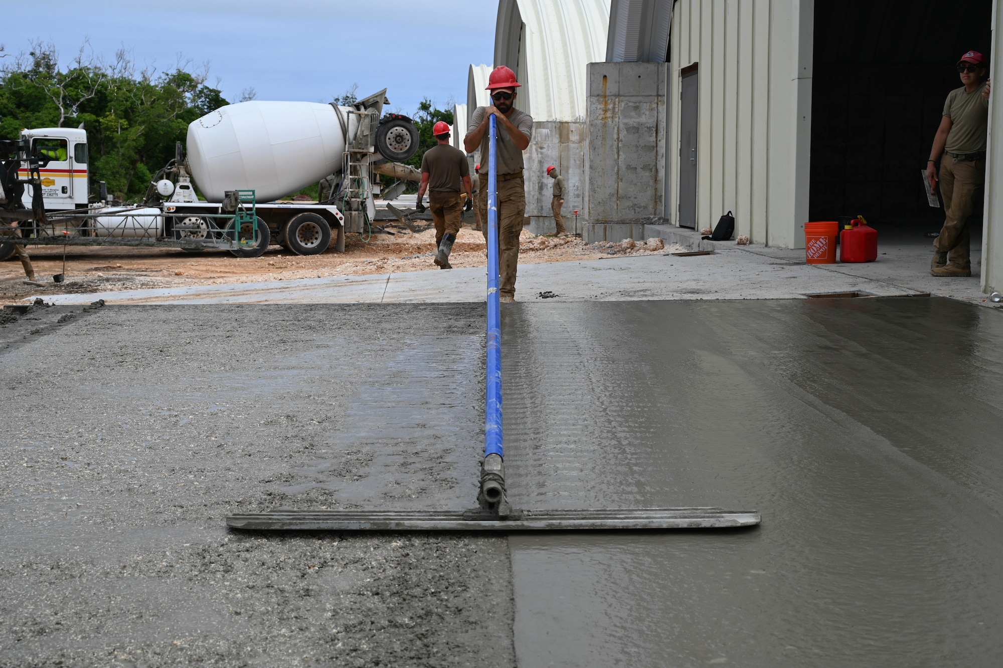 An Airman pushes down on a bull float in order to smooth out the surface of the concrete.