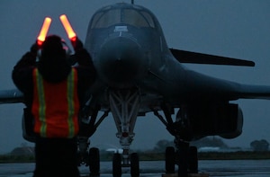 Airman 1st Class Cameron Iweanoge, 9th Expeditionary Bomb Squadron crew chief, guides a B-1B Lancer from Dyess Air Force Base, Texas, into a parking spot during Bomber Task Force 24-2 at Morón Air Base, Spain, March 24, 2024. The rotational deployment of U.S. bomber forces in Europe is evidence of the enduring commitment to NATO Allies and to a whole, free and peaceful Europe. U.S. forces are ready, postured and well-prepared to integrate with host-nation Allies and partners to deter threats and defend the Alliance. (U.S. Air Force photo by Staff Sgt. Holly Cook)