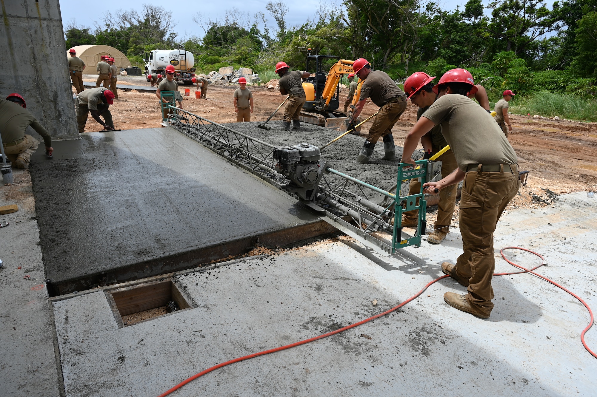 Airmen work together to smooth out the coarse aggregate.