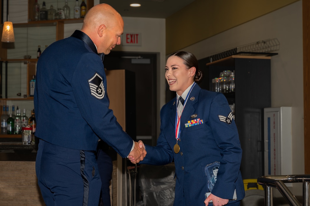 U.S. Air Force Master Sgt. Benjamin Malotte, 51st Fighter Wing Airman Leadership School commandant, left, and Senior Airman Ellie Wilbourn, 7th Air Force Joint Worldwide Intelligence Communications System administrator, shake hands during an ALS graduation at Osan Air Base, Republic of Korea, March 21, 2024. Wilbourn was the John L. Levitow award recipient for her outstanding qualities of leadership, followership and service. (U.S. Air Force photo by Airman 1st Class Chase Verzaal)