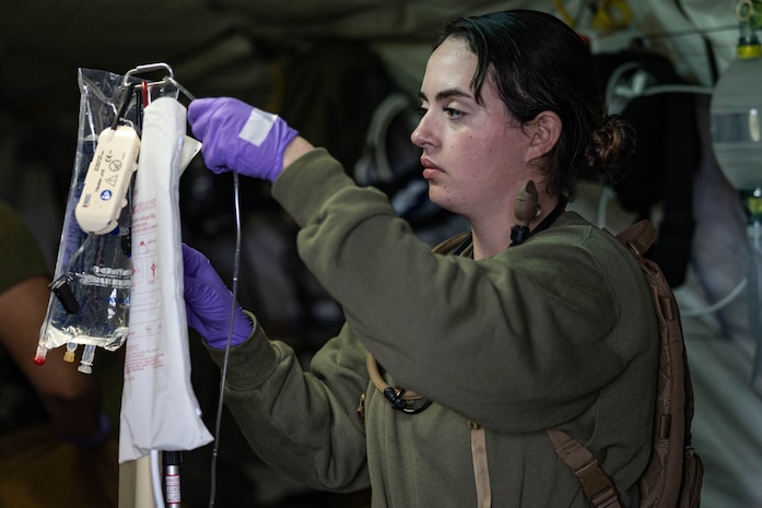 U.S. Navy Hospital Corpsman 3rd Class Megan Evans, a native of Houston, Texas and a field medical service technician with 1st Medical Battalion, 1st Marine Logistics Group, hangs a bag of saline for a simulated casualty at a Marine Corps Combat Readiness Evaluation on Camp Pendleton, California, Feb. 23, 2024. The MCCRE is a culminating event that certifies the Marines and Sailors to practice tactical combat casualty care, chemical, biological, radiological, and nuclear skills in a field environment. (U.S. Marine Corps photo by Cpl. Savannah Norris)