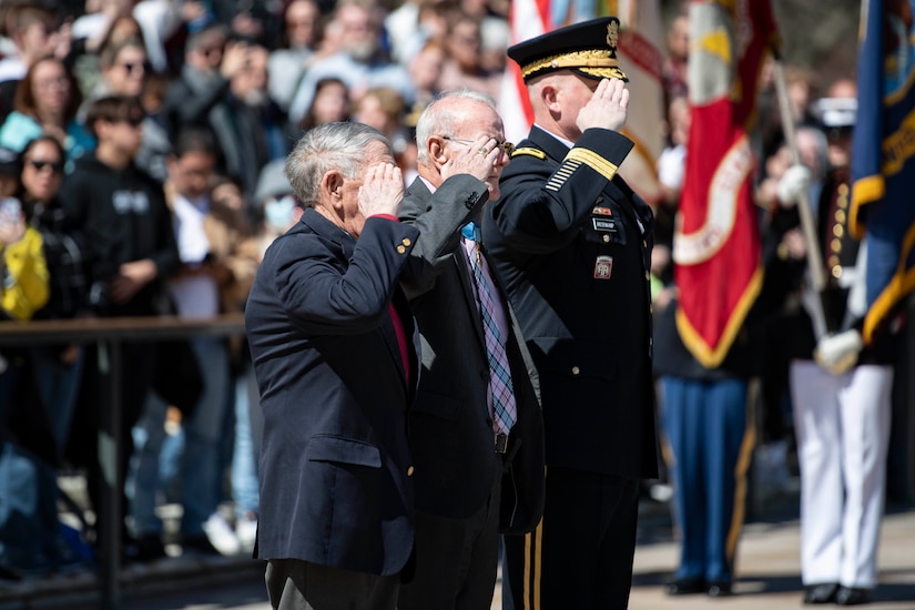 Three people standing next to each other salute.