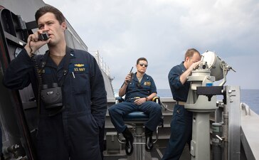 Cmdr. David Gardner, center, commanding officer of the Independence-variant littoral combat ship USS Mobile (LCS 26), Lt. j.g. Andrew Halus, left, electronics maintenance officer, and Lt. Jordan Fillmore, weapons officer, track and report movements between Mobile and the Lewis and Clark-class dry cargo and ammunition ship USNS Wally Schirra (T-AKE 8) to position for an underway replenishment in the South China Sea.
