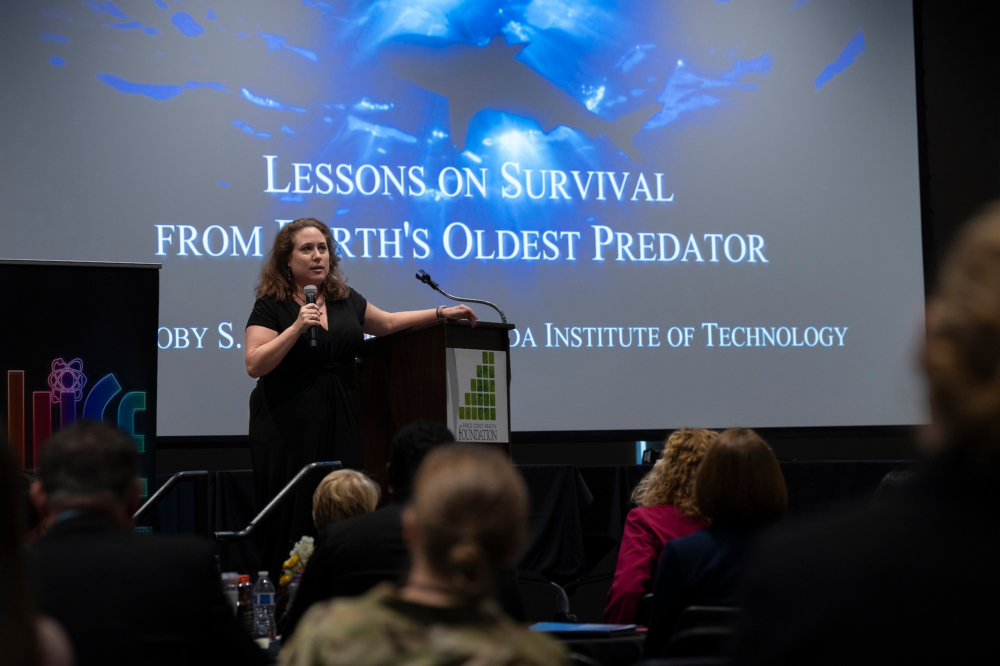 Dr. Toby Daly-Engel, assistant professor at Florida Tech and director of the university’s Shark Conservation Lab, speaks to attendees at the 2024 Women in Science and Engineering Symposium March 12, hosted by the Air Force Technical Applications Center at Patrick Space Force Base, Fla.  Daly-Engel’s presentation entitled “Lessons on Survival from Earth’s Oldest Predator” was one of several briefings aimed at encouraging young women to pursue careers in science and technology.   (U.S. Air Force photo by Matthew S. Jurgens)