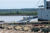 A photo of a Humvee driving up the ramp of a ship.