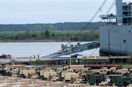A photo of a Humvee driving up the ramp of a ship.